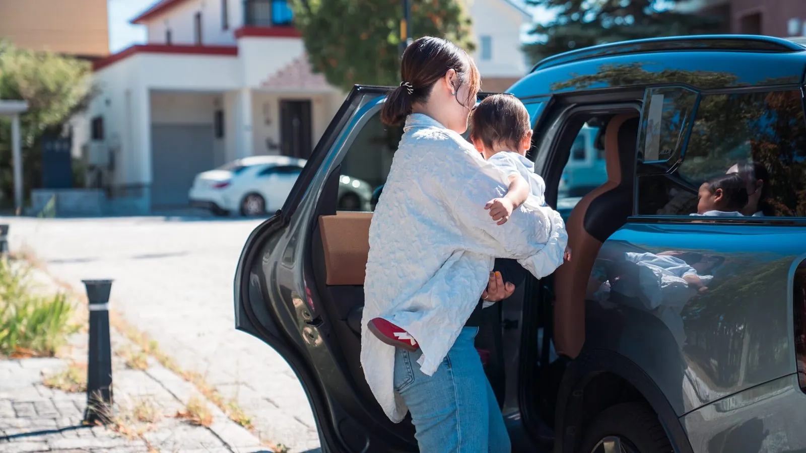 子どもを抱いて車から降ろす母親