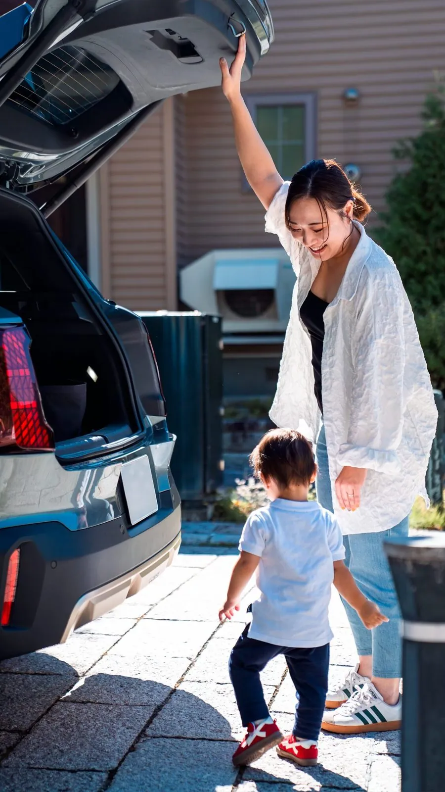 車のトランクを開ける母親と、駆け寄る子ども