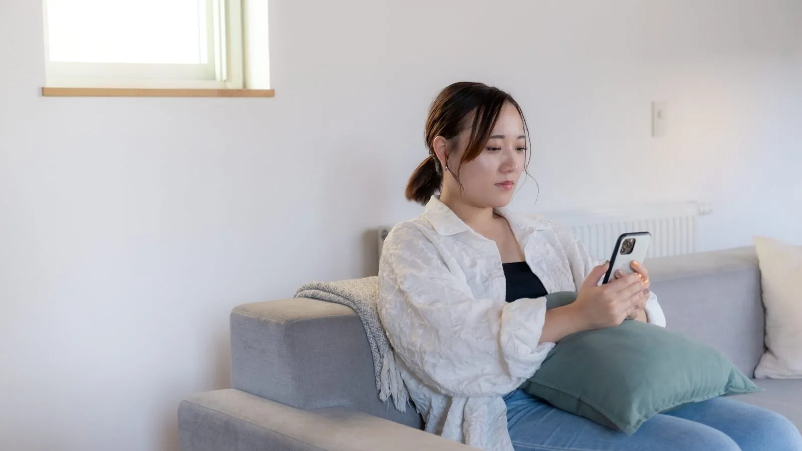 ソファでスマートフォンを手にする女性